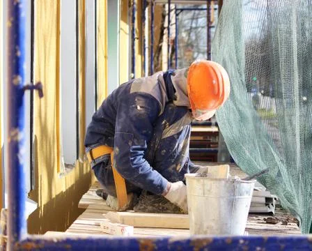 The worker makes the sladding of windows in the restored building in the city Stock Photos