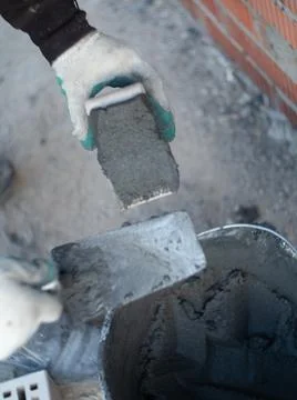 Worker making a gray brick wall on a construction site Stock Photos