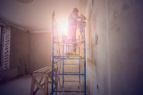 Worker is making a technological hole for electrical cabel in the wall in Stock Photos
