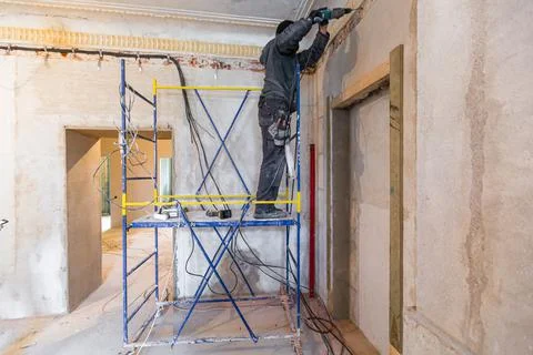 Worker is making a technological holes for electrical cabel in the wall in Stock Photos