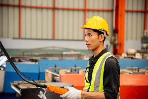 Worker man hand push remote control switch for overhead crane in factory 库存照片