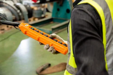 Worker man hand push remote control switch for overhead crane in factory Stock Photos