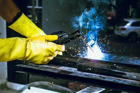 Worker man hand with yellow gloves welding Stock Photos