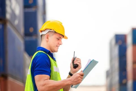 Worker man in hard hat holding clipboard checklist and talks on two-way radio 스톡 사진