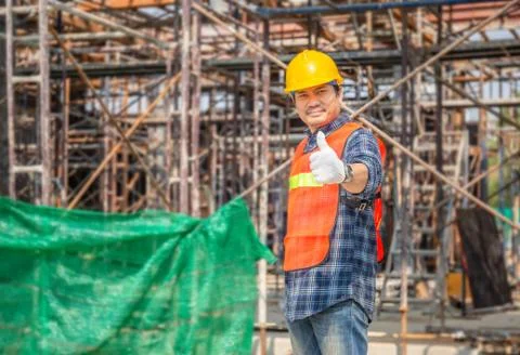 Worker man in hard hat standing with giving thumb up at construction site Stockfoto's