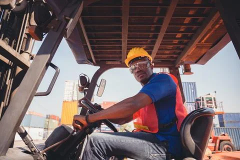 Worker man in hardhat sitting in container stackers at containers cargo Stockfoto's