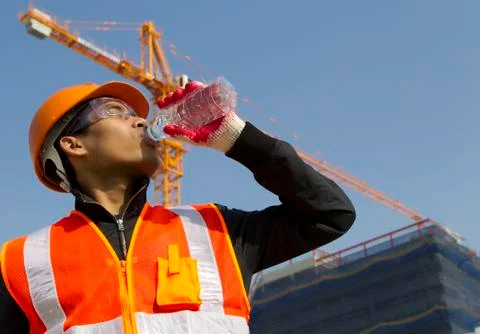 Worker man  as he drinks from a plastic water bottle Stock Photos