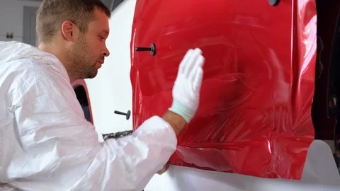 Worker man is installing vinyl tape on car body Stock Footage 121418647