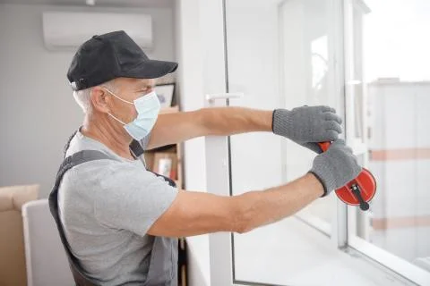 Worker man installs plastic windows and doors with double-glazed white 스톡 사진