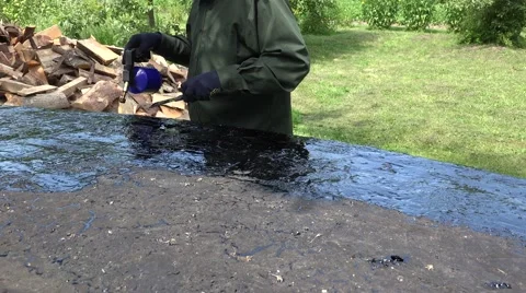 Worker man lays hot tar with gas burner priming on boat bottom. 4K Stock Footage 67636381