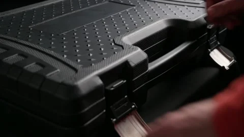 Worker man in red shirt opening black toolbox with silver chrome tools in dark Stock Footage 157146535