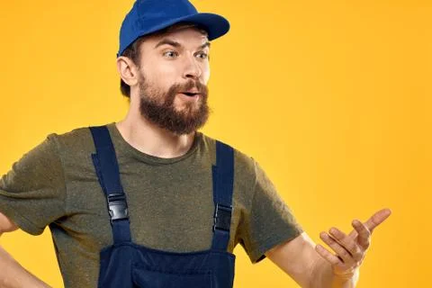 Worker man in uniform worker service yellow background emotion Stock Photos