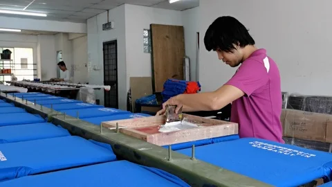 Worker man using Silk screen printing on clothing fabric technique Stock-Footage 121945346