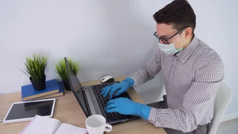 Worker man wearing protective mask, gloves, shirt sits by desk, use laptop, type Stock Footage 131472229