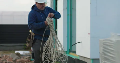 Worker managing and bundling cables near construction structure, preparing .. Stock Footage 292447664