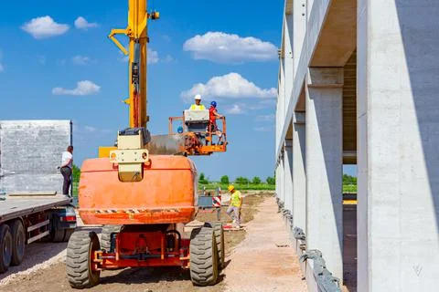 Worker is managing a cherry picker at building site Stock Photos