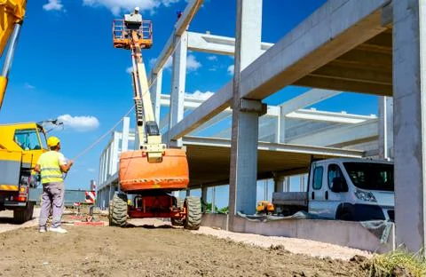 Worker is managing an elevated cherry picker at building site Stock Photos