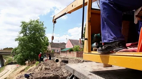 Worker is managing mobile crane and pulling huge pipe in the trench. Stock Footage 72978398