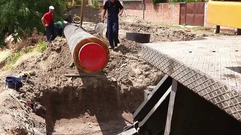 Worker is managing mobile crane and pulling huge pipe in the trench. Stock Footage 72978460