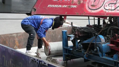 A worker manipulates with a heavy concrete tubes on the back of a truck Video stock 220169753