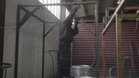 Worker manually installing metal wire for knitting mesh fence on machine in hall Stock Footage 83820915