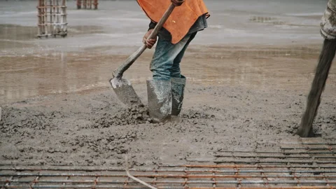Worker manually leveling wet concrete with a shovel Stock Footage 305886618