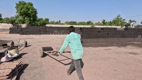 Worker Manually Moving Stacked Concrete Bricks with Hand Trolley in Industrial Stock Footage 340505448