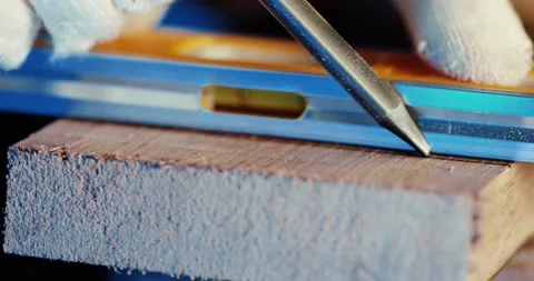 The worker marks the board for sawing with a pencil and ruler. With a gloved Video stock 166293350