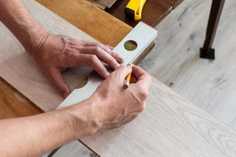 Worker marks the length of the laminate Stock Photos