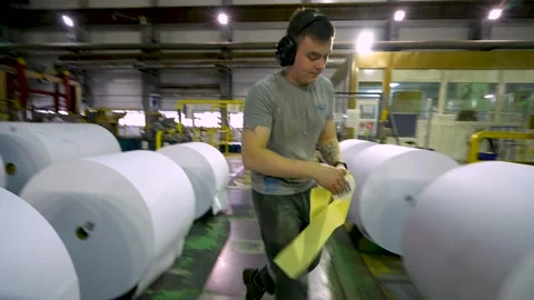 A worker marks rolls of white paper. Paper production Stockbeeldmateriaal 325789498