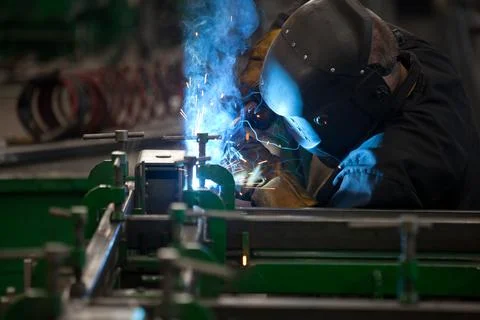 Worker in mask, in the process of welding metal with bright light, smoke and Stock-Fotos
