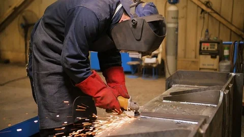Worker in mask use angle grinderon metal construction metal. Sparks slowly turns Stock Footage 72697397
