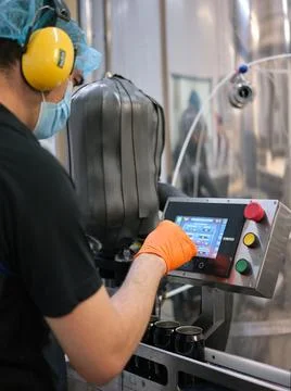Worker with mask working with an electronic machine in a craft beer factory Stock Photos