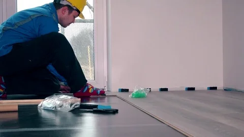 Worker master in blue work wear install the laminate floor Stock Footage 77833492