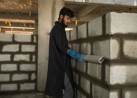 A worker may be seen using a level to inspect a brick wall. Stock Photos