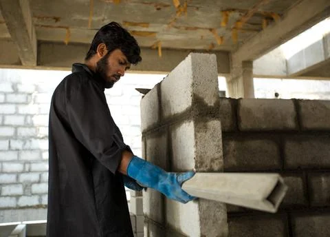 A worker may be seen using a level to inspect a brick wall Stock Photos
