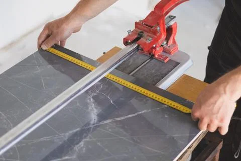 Worker is measure ceramic tile for a cutting. Maintenance repair in the fla.. Stock Photos
