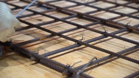 Worker measures distance between armature on wooden floor with roulette. Video stock 126357202