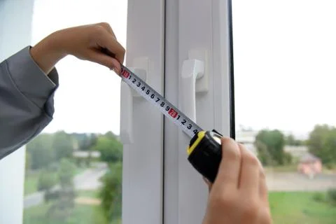 A worker measures the handles of a plastic window with a ruler. Stock Photos