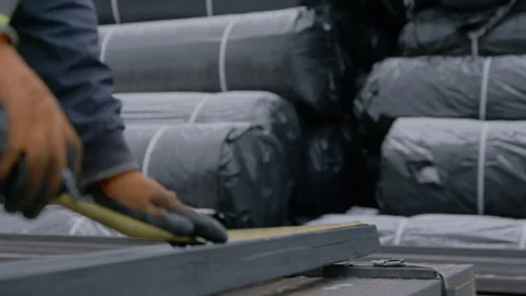 Worker measures length of profile pipe at construction site Stockbeeldmateriaal 255558060