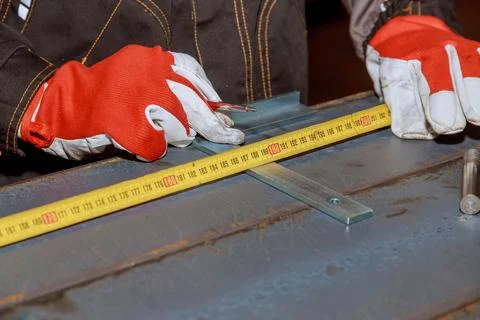Worker measures markings on a metal surface for drilling holes. Marking tools Stock Photos