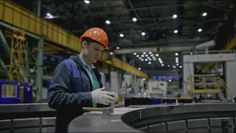 Worker measures structural part at factory. Stock clip. Worker in helmet at Stock Footage 281330865