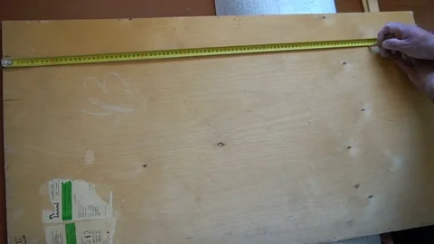 Worker measures with tape measure hardwood plywood Stock Footage