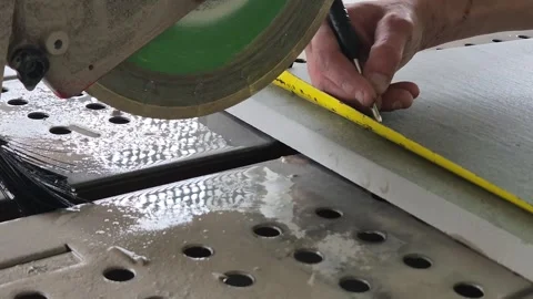 Worker measuring and marking a tile slab before cutting with a wet saw Stock Footage 333588406