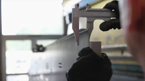Worker measuring bent metal panel with caliper Stock Footage 317254128