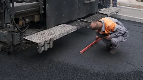 Worker measuring flat asphalt surface with spirit level at construction site Stock Footage 339802394