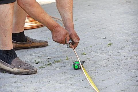 A worker measuring the length of a copper pipe with a tape measure Stock Photos