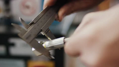 Worker measuring metal component with vernier caliper in industrial workshop Stockbeeldmateriaal 155207073