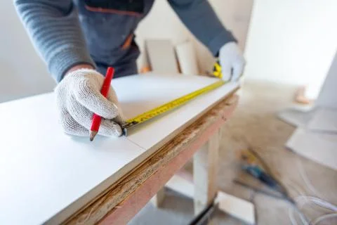Worker is measuring the plastic detail before it cutting in apartment that is Stock Photos