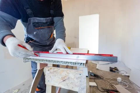 Worker is measuring the plastic detail before it cutting in apartment that is Stock Photos